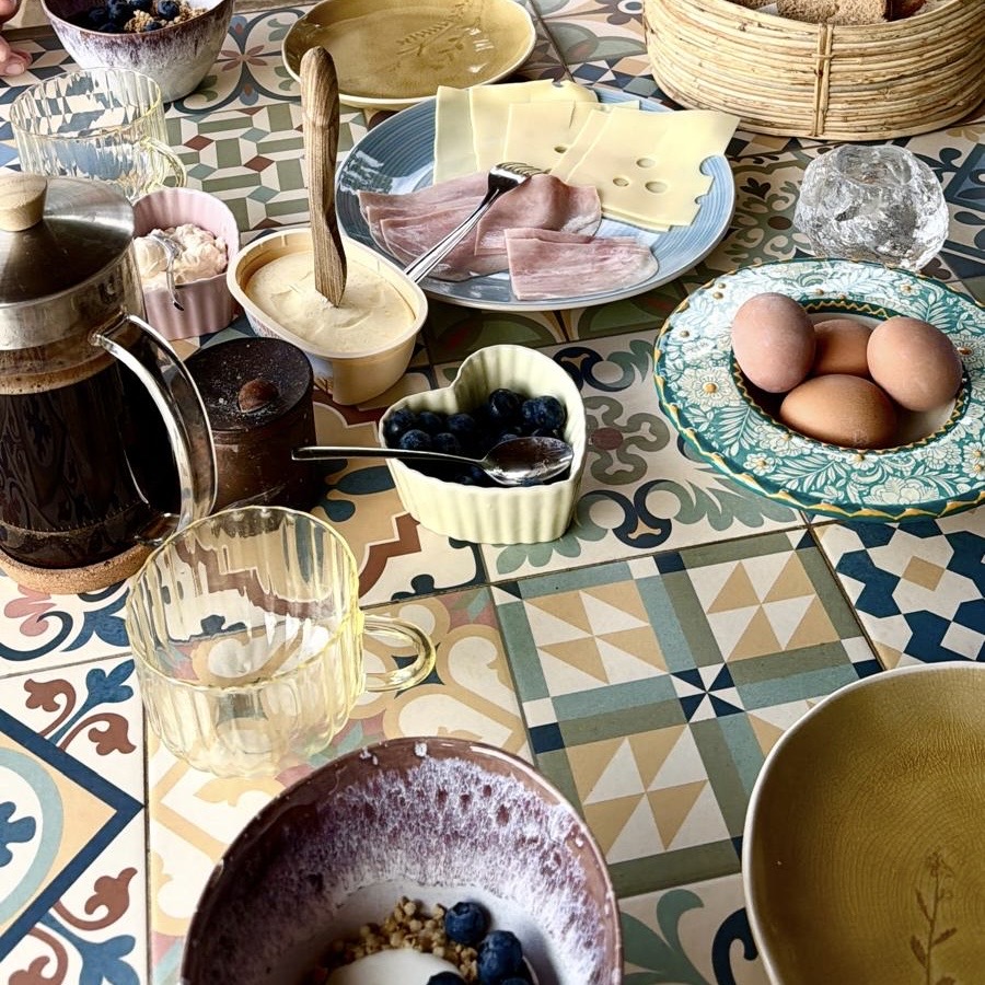 Breakfast table with coffee, eggs, cheese and berries on Andalusian tiles